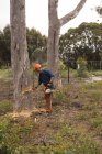 Вид сбоку на лумберджек, проверяющий ствол дерева в лесу — стоковое фото