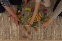 Багатоповерхова сім'я грає з будівельними блоками у вітальні вдома — стокове фото