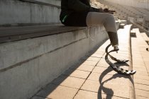 Низкая часть спортсмена-инвалида с помощью мобильного телефона на спортивном объекте — стоковое фото