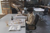 Ejecutiva masculina usando auriculares de realidad virtual en la mesa en la oficina - foto de stock