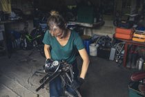 Female mechanic repairing motorbike in repair garage — Stock Photo