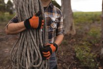 Mid section of lumberjack holding rope in forest — Stock Photo