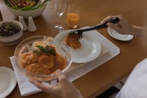 Primer plano de la mujer que sirve comida en un plato en la mesa de comedor - foto de stock