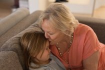 Бабуся цілує свою онуку у вітальні вдома — стокове фото