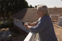 Удумлива старша жінка має каву на терасі — стокове фото