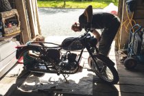 Mécaniciens masculins et féminins réparer moto dans le garage de réparation — Photo de stock