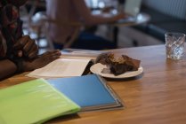 Prato de sobremesa e empresário lendo um livro na cafetaria no escritório — Fotografia de Stock