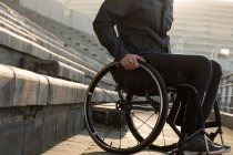 Baixa seção de atleta com deficiência em movimento com cadeira de rodas em local de esportes — Fotografia de Stock