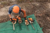 Lumberjack verificando motosserra na floresta — Fotografia de Stock