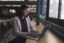 Жінка-виконавця, що працює на ноутбуці за столом в офісі — стокове фото
