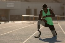 Male disabled athlete checking time on a running track — Stock Photo