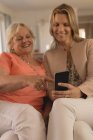Мати і дочка використовують мобільний телефон у вітальні вдома — стокове фото