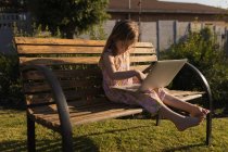 Mädchen mit Laptop im Garten an einem sonnigen Tag — Stockfoto