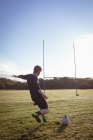 Jogador de rugby chutando bola de rugby no campo em um dia ensolarado — Fotografia de Stock