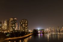 Modern downtown with light trail and river — Stock Photo