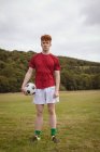 Молодий футболіст стоїть з футбольним м'ячем у полі — стокове фото