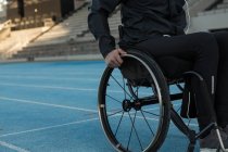 Mid section of disabled athlete moving with wheelchair at sports venue — Stock Photo