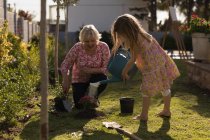 Бабуся і онука посаджують в саду в сонячний день — стокове фото