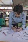 Männliche Führungskraft nutzt Mobiltelefon, während sie im Büro an einem Entwurf arbeitet — Stockfoto