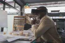 Чоловічий виконавчий директор, використовуючи гарнітуру віртуальної реальності за столом в офісі — стокове фото