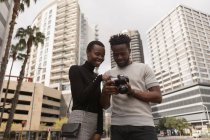 Человек просматривает фотографии на цифровой камере на городской улице — стоковое фото