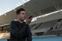 Athlete talking on mobile phone at sports venue — Stock Photo