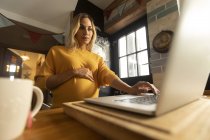 Concentrated pregnant woman using laptop at home — Stock Photo