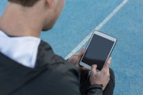 Primer plano del atleta utilizando tableta digital en el lugar de los deportes - foto de stock