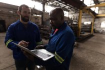Dos herrero discutiendo sobre portátil en el taller - foto de stock