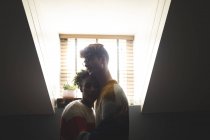 Jeune couple embrassant à la maison dans rétro-éclairé — Photo de stock