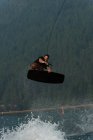 Junger Mann springt beim Wakeboarden in Fluss über Wasser — Stockfoto