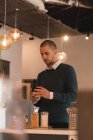 Мужчина смотрит на чашку кофе в интерьере кафе — стоковое фото