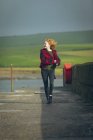 Happy redhead woman walking on ocean shore. — Stock Photo