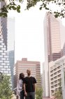 Молодая пара, стоящая вместе против городских зданий — стоковое фото