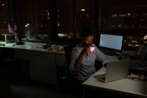 Женщина-руководитель пьет кофе во время использования ноутбука в офисе ночью — стоковое фото
