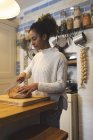 Frau schneidet Laib Brot in Küche zu Hause — Stockfoto