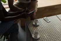 Primo piano di coppia utilizzando il telefono cellulare nel caffè — Foto stock