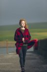 Thoughtful redhead woman walking in windy coast. — Stock Photo