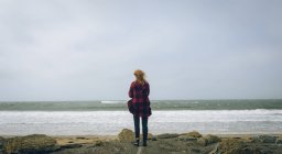 Vue arrière de rousse femme debout dans la plage venteuse . — Photo de stock