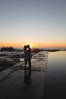 Пара обіймати один одного на набережній під час заходу сонця — стокове фото