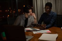 Dirigenti che discutono su tablet digitale in ufficio di notte — Foto stock