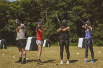 Grupo de pessoas treinando tiro com arco no acampamento de inicialização à luz do sol — Fotografia de Stock