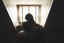 Rear view of couple embracing at home in backlit — Stock Photo