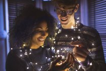 Glückliches Paar spielt zu Hause mit Lichterketten — Stockfoto