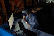 Vista ad alto angolo del dirigente maschile utilizzando cuffie realtà virtuale in ufficio di notte — Foto stock