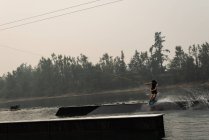 Jovem atleta wakeboarding no rio ao entardecer — Fotografia de Stock