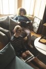 Casal usando laptop e livro de leitura na sala de estar em casa — Fotografia de Stock