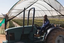 Uomo che parla al cellulare seduto sul trattore alla fattoria dei mirtilli — Foto stock