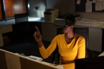 Жіночий виконавчий за допомогою віртуальної реальності гарнітуру в офісі вночі — стокове фото