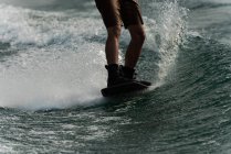 Sección baja del hombre wakeboarding en el agua del río - foto de stock